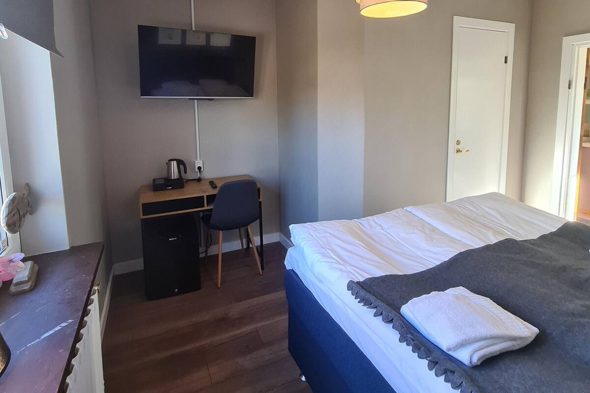 Une chambre à coucher avec un lit, un bureau, une chaise, un téléviseur et une porte.