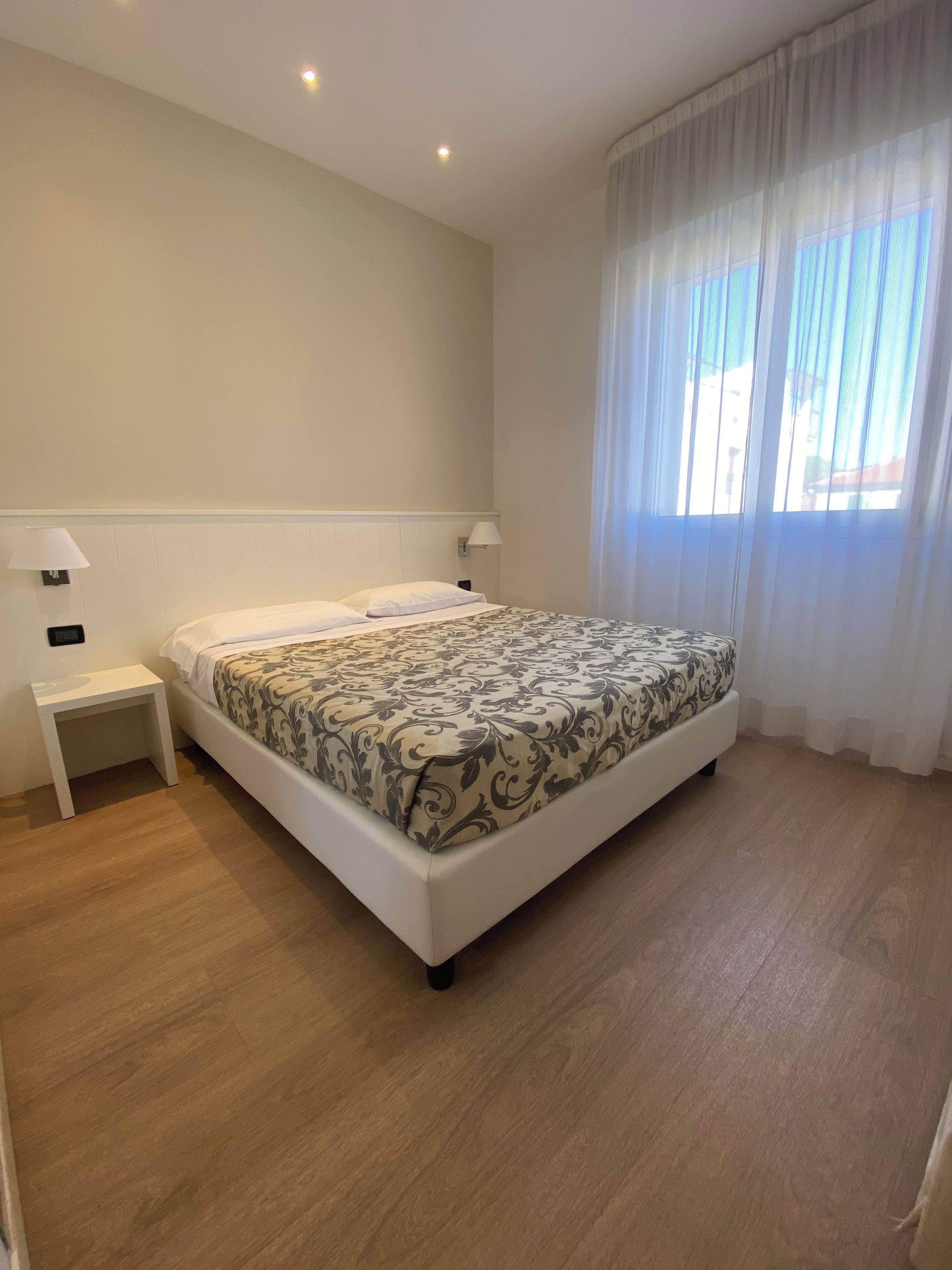 Une chambre d’hôtel avec un lit, des tables de chevet et une fenêtre avec des rideaux.