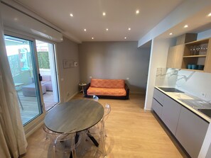 Une cuisine moderne avec une table à manger, un canapé et une porte-fenêtre coulissante donnant sur un espace extérieur.