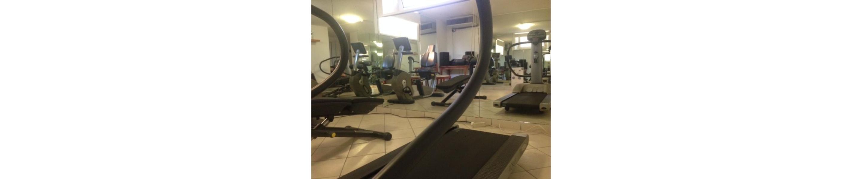 Un gimnasio con cintas de correr, bicicletas estáticas y elípticas.