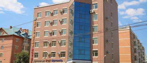 A multi-story hotel with a red brick facade and a blue glass section.