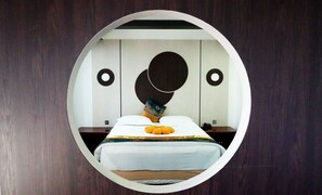 A circular mirror reflecting a bedroom with a bed, pillows, and a bedside table. - Zolo Hotel (Ulaanbaatar)