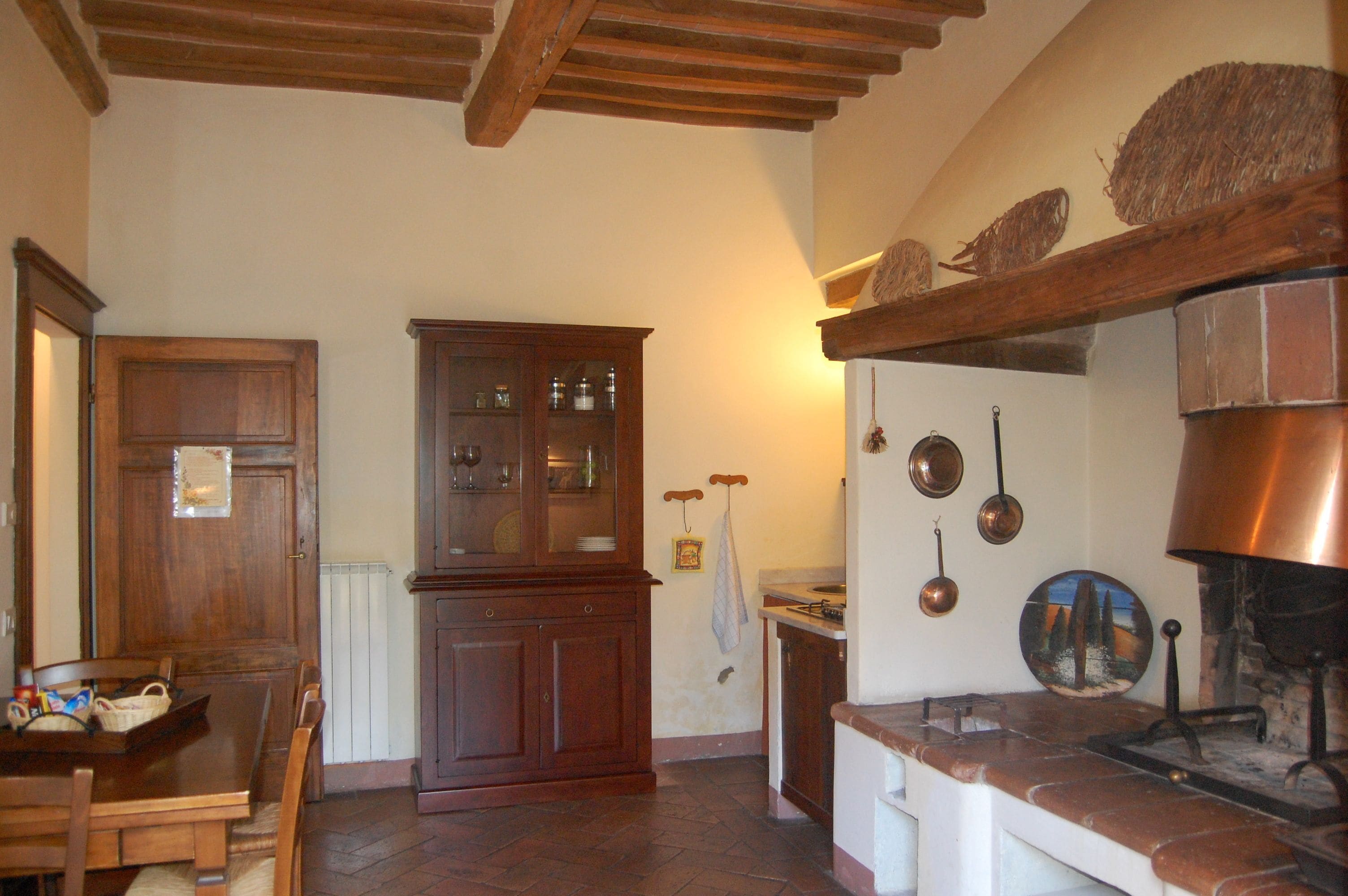 A traditional kitchen with wooden cabinets, a dining table, and a hanging pot rack.