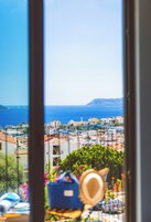 Vista de un pueblo costero desde una ventana, que incluye edificios, una mezquita y el mar al fondo.