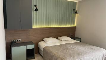 A modern bedroom with a bed, bedside tables, a wardrobe, and a wall-mounted light fixture.