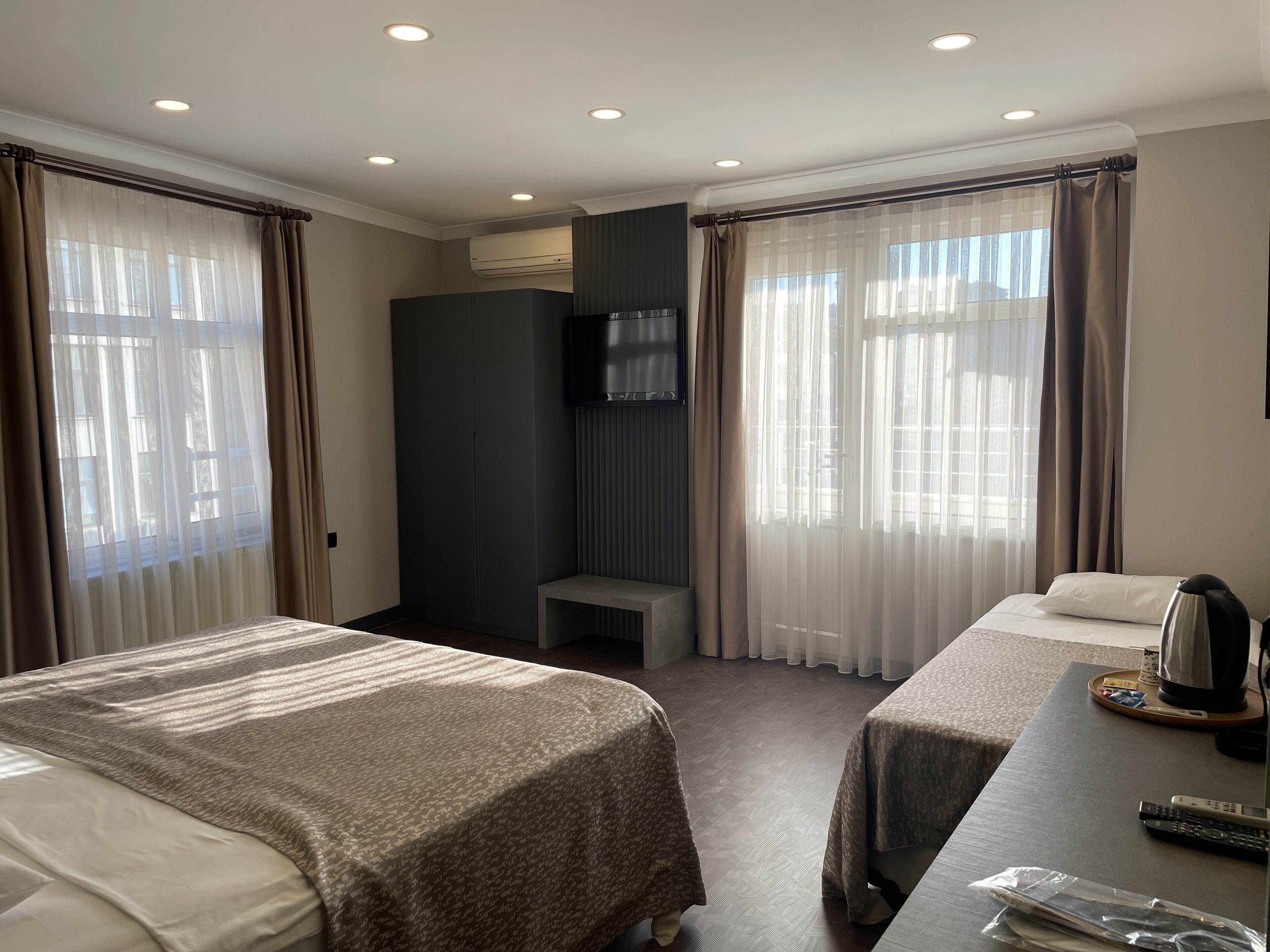 A hotel room with two beds, a TV, and a small seating area.