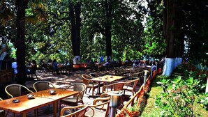 An outdoor cafe with wicker tables and chairs, surrounded by trees. - Keles Hotel (Rize)