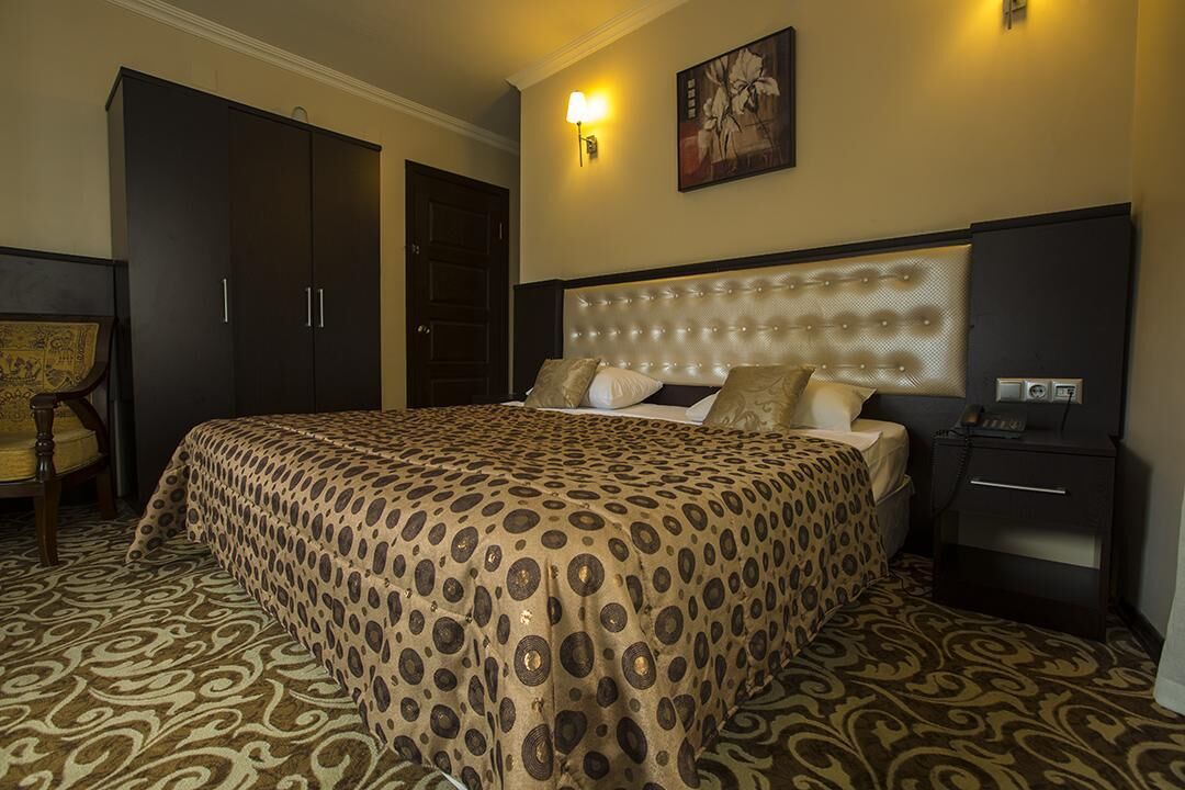 Ein Hotelzimmer mit einem großen Bett, einem Nachttisch, einem Sessel und einem Kleiderschrank.