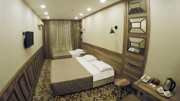 A hotel room with two beds, a desk with a telephone and a coffee maker, a mirror, and a patterned carpet.