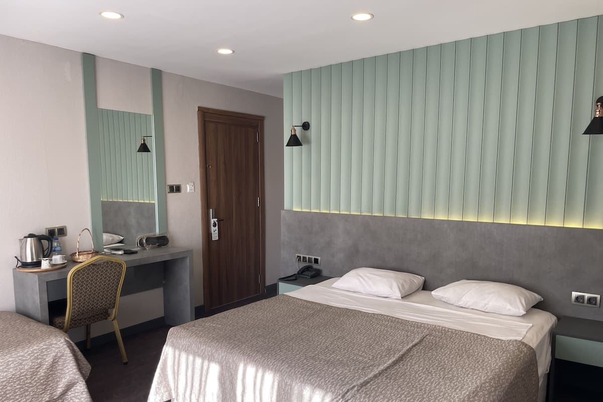 Una habitación de hotel con cama, escritorio, silla, armario y espejo.