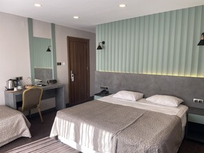 A hotel room with a bed, a desk, a chair, a wardrobe, and a mirror. - Keles Hotel (Rize)