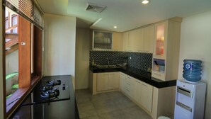 Una cocina compacta con estufa a gas, dispensador de agua y salpicadero de azulejos.