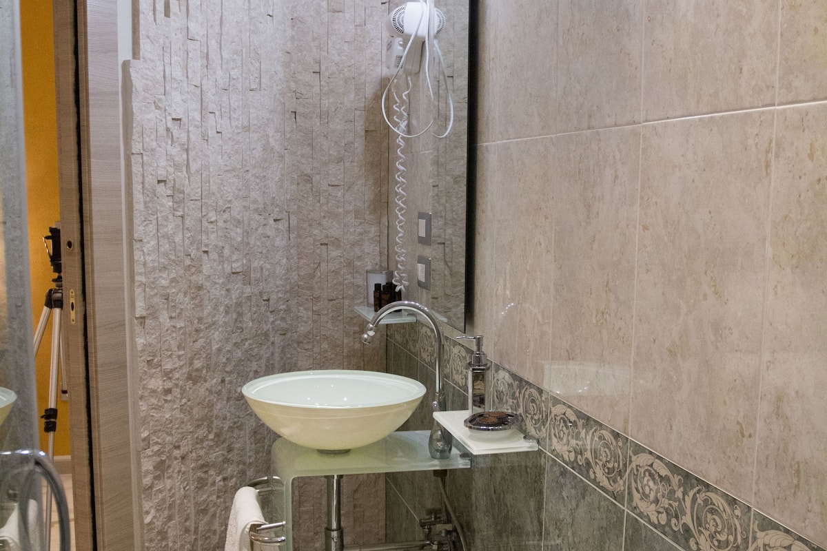 A bathroom with a glass sink, a towel rack, and a mirror.