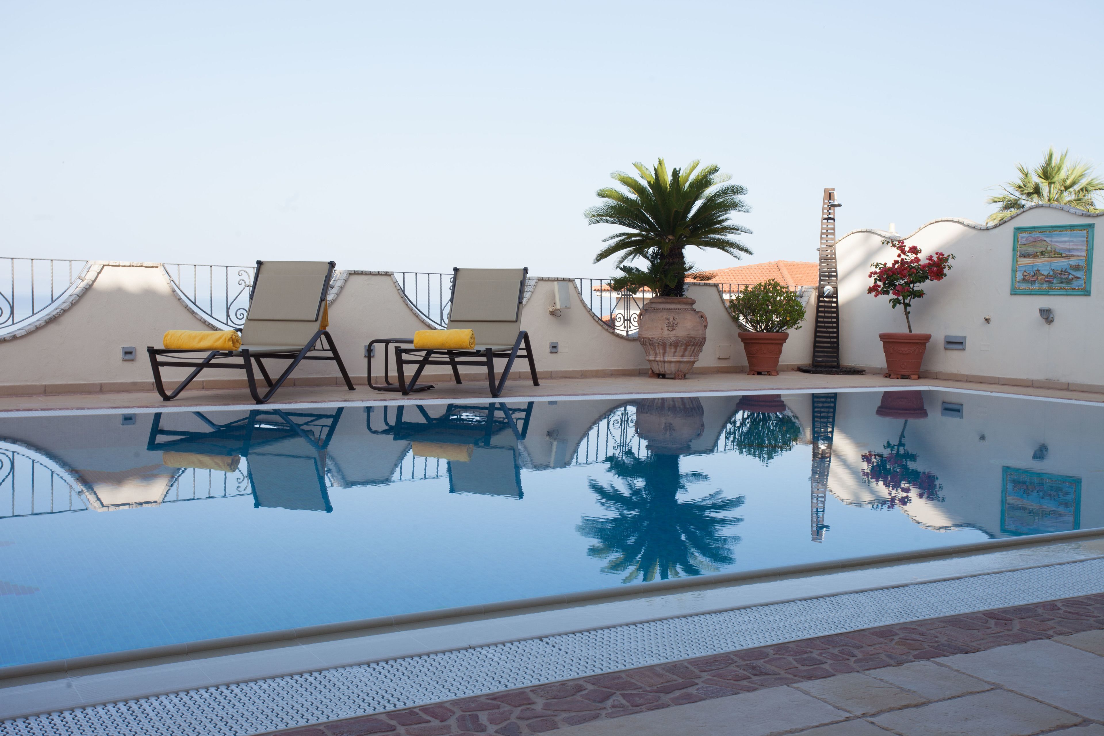 Una piscina en la azotea con dos tumbonas y plantas en macetas.