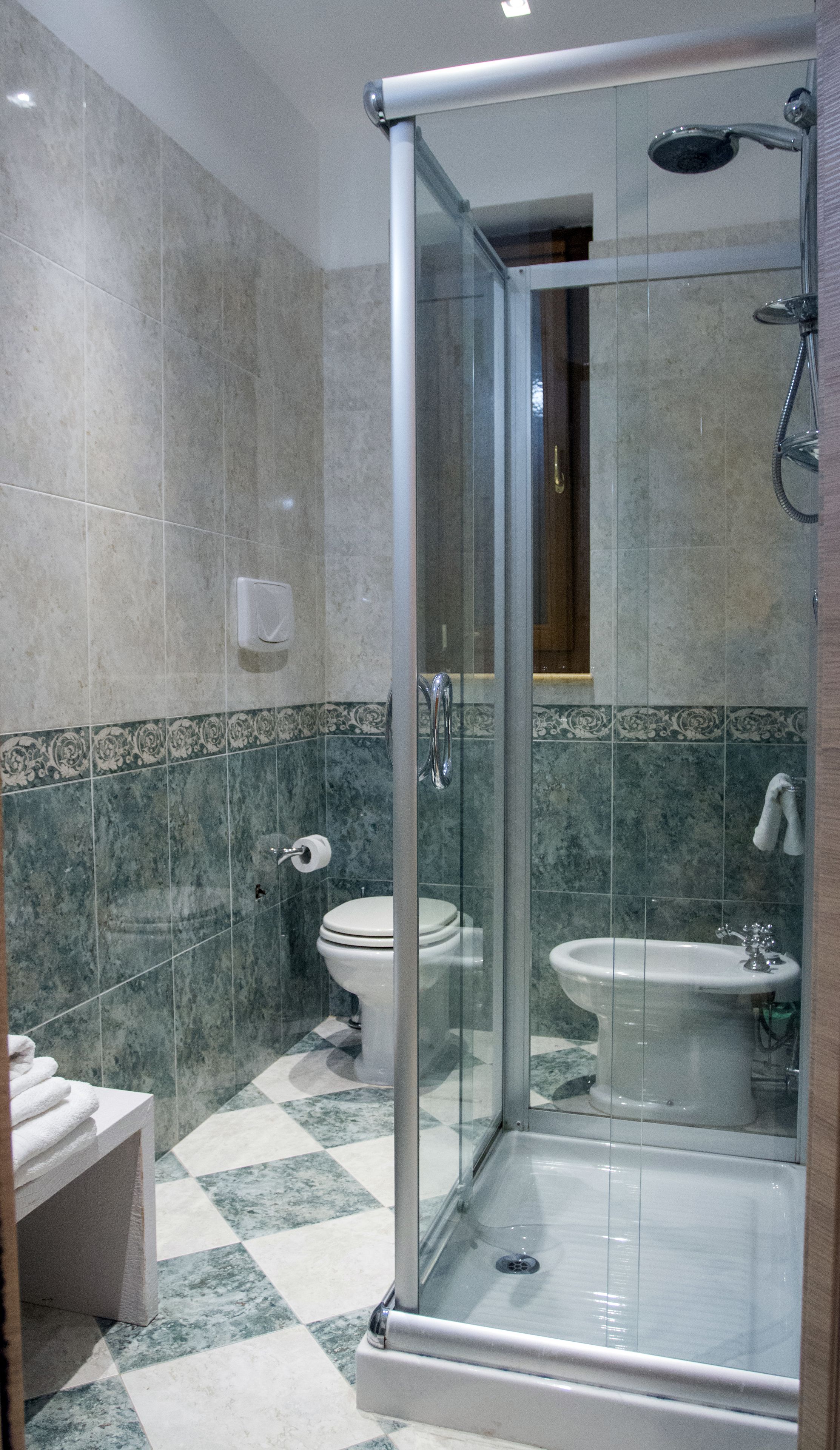 Un bagno moderno con doccia vetro, water e bidet.