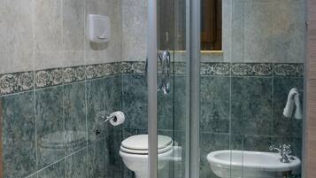 Un bagno moderno con doccia vetro, water e bidet.