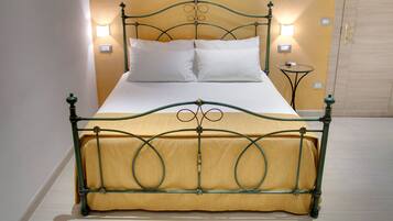 A bed with a green metal frame and a yellow upholstered headboard. There are two bedside tables with lamps on either side of the bed.