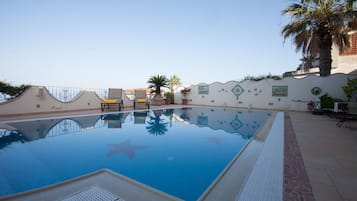 Una piscina al aire libre de temporada, sillones reclinables de piscina