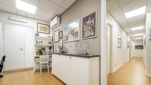 A reception area with a reception desk, chairs, a coffee machine, and framed artwork on the walls. - Dome (Cagliari)