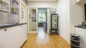 A hallway with a wooden floor, a counter with numbered cabinets, a refrigerator, and a trash can. - Dome (Cagliari)