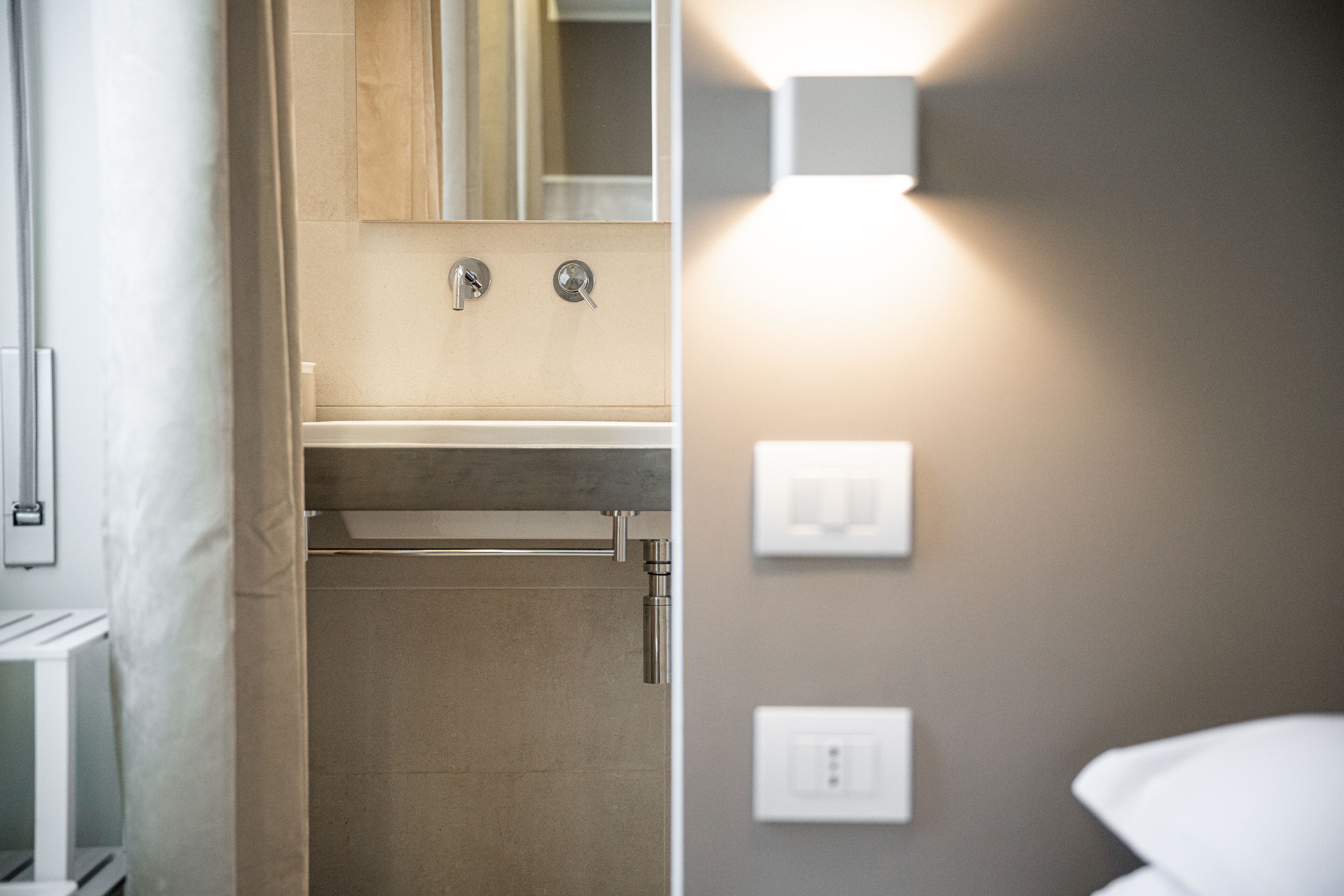 Un baño con lavamanos, espejo, toallero e iluminación en la pared.