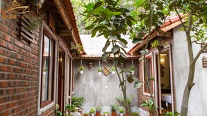 A courtyard with brick walls, potted plants, and a tiled floor. - Amira Homestay (Nam Hoa Lu)