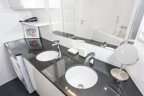 Casa de banho moderna com duas pias, um espelho grande e um porta-toalhas.