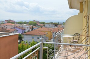 A balcony with a view of a residential area, including houses with red-tiled roofs and a mountainous background. - Hotel Carolin (Rimini)