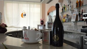 Una zona de bar con una botella de Prosecco y una taza de café.