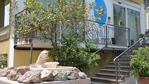Un edificio con una fuente de piedra, una escalera y un balcón con barandillas de metal.