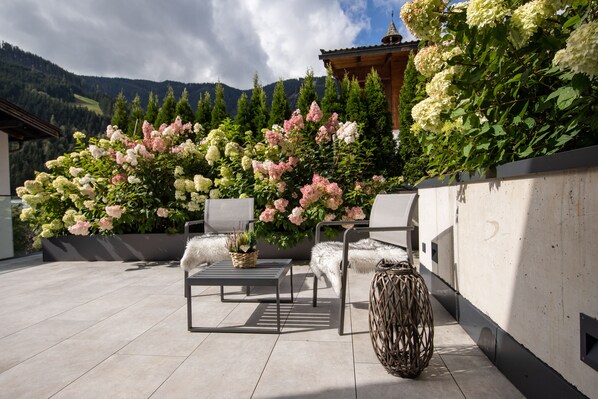 A patio with outdoor furniture, a decorative vase, and a large flower arrangement.