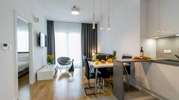 Een moderne keuken met een eetgedeelte, houten vloeren en uitzicht op de woonkamer.