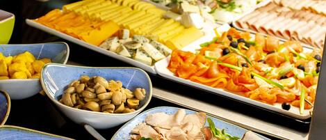 A buffet with various dishes including meats, cheeses, and vegetables.