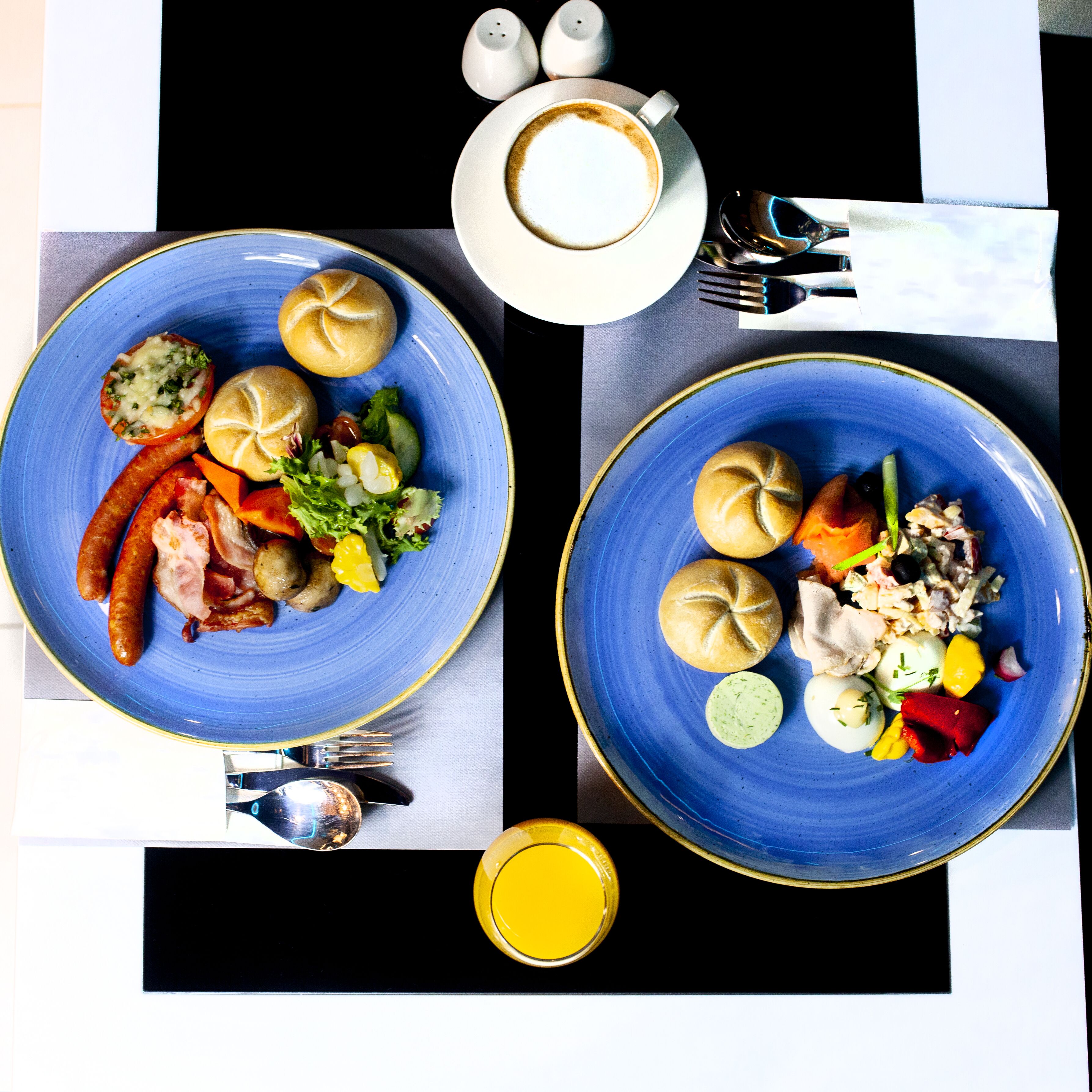 Deux assiettes de nourriture, une tasse de café et une bouteille de jus sur une table.