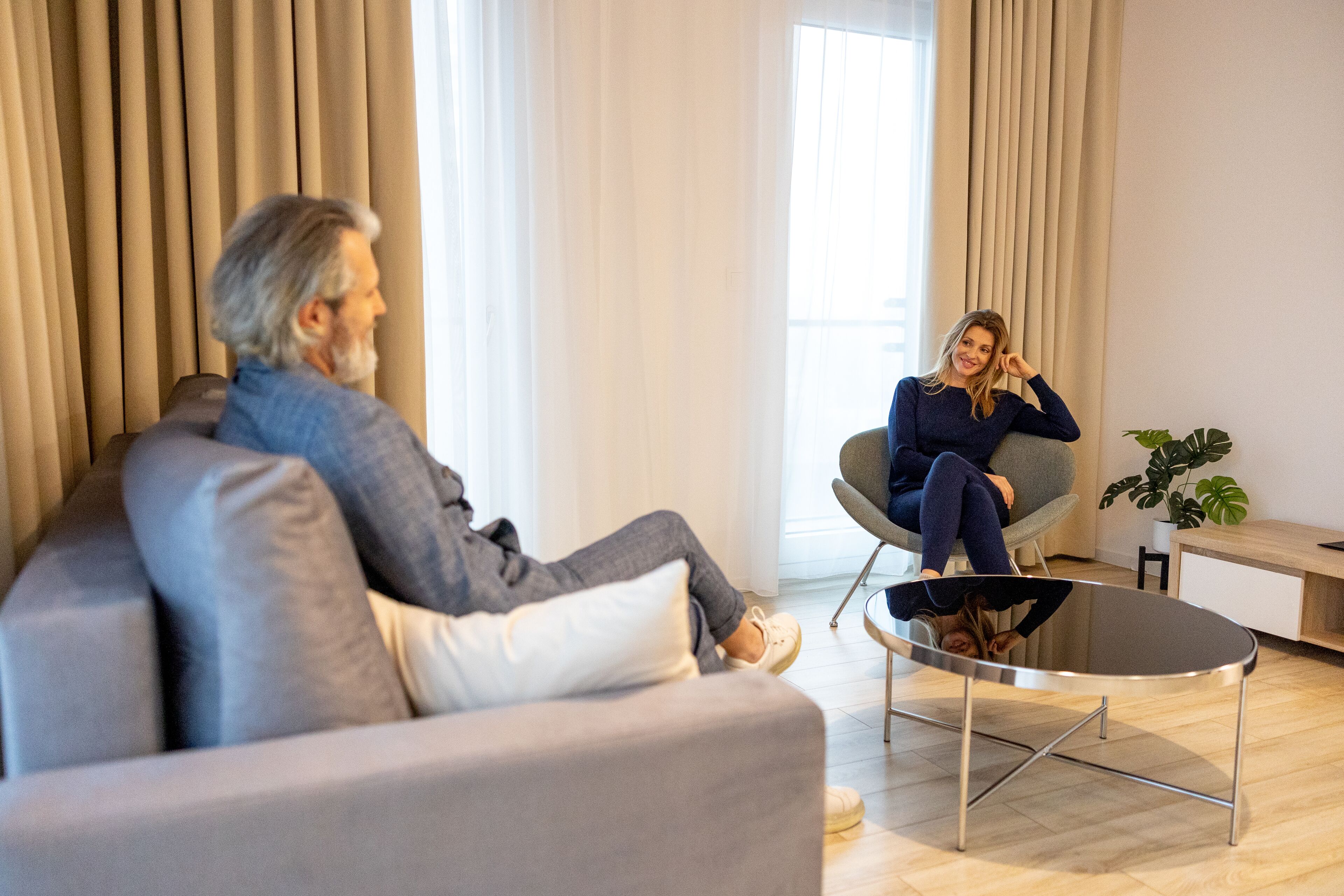 A modern living room with a grey sofa, a round coffee table, and a potted plant.