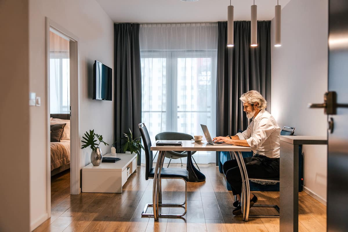 Ein modernes Wohnzimmer mit Essbereich, einem flachbildfernseher an der Wand und einem großen Fenster mit Vorhängen.