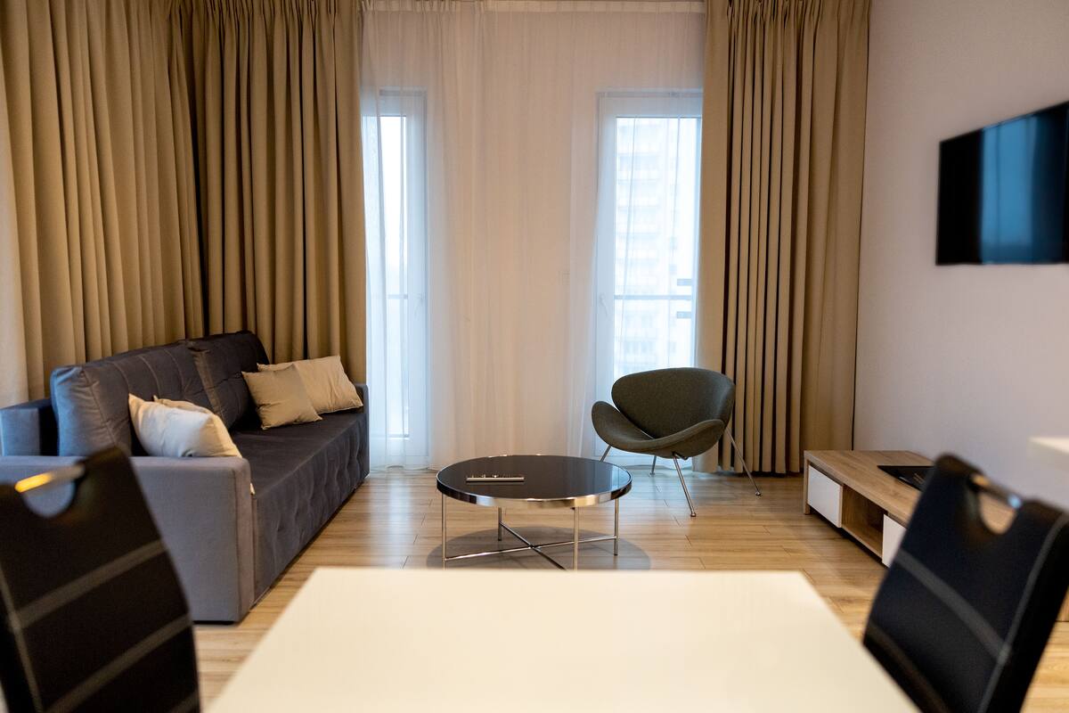 Ein modernes Wohnzimmer mit einer Couch, einem runden Couchtisch und einem Sessel.