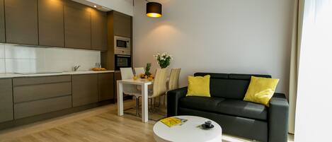 A modern living room with a black sofa, yellow pillows, a white coffee table, and a brown armchair.