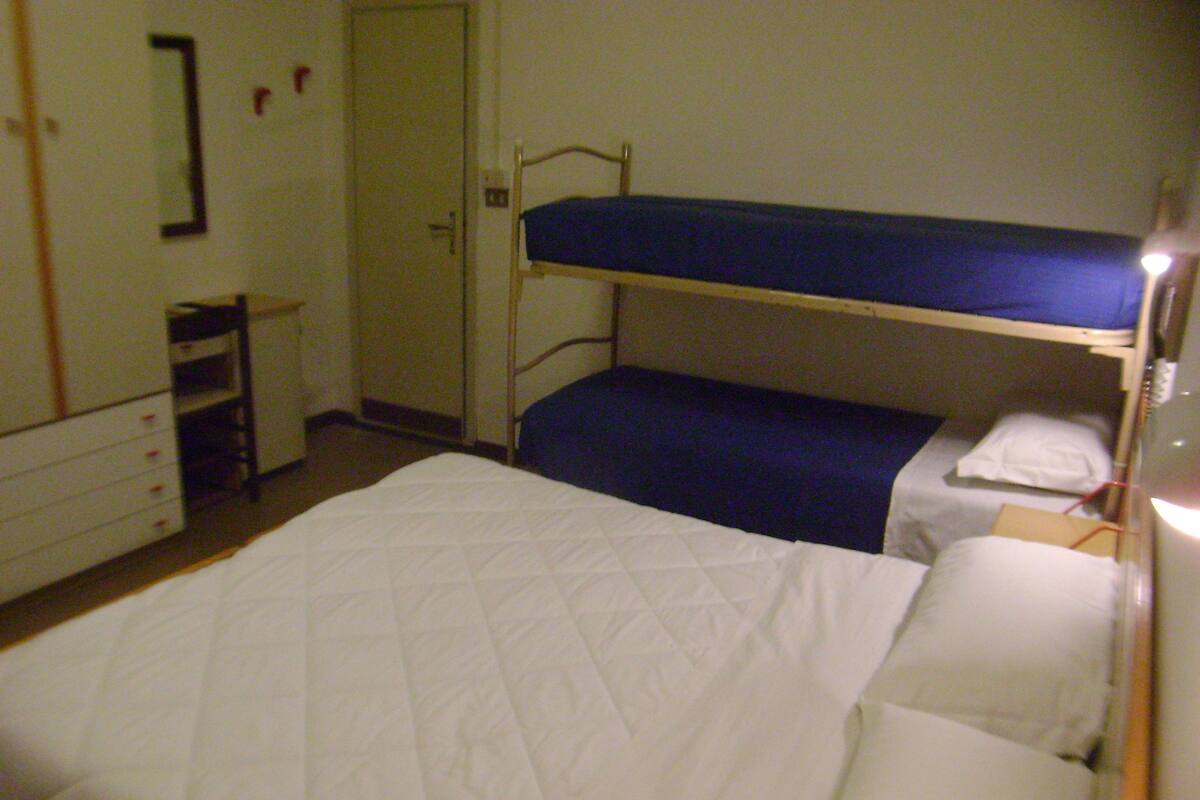 A single-bed room with a bunk bed and a desk.
