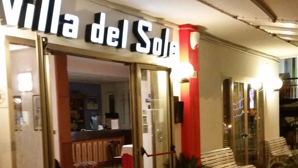 The entrance to Villa del Sole with a wooden deck and outdoor seating area.