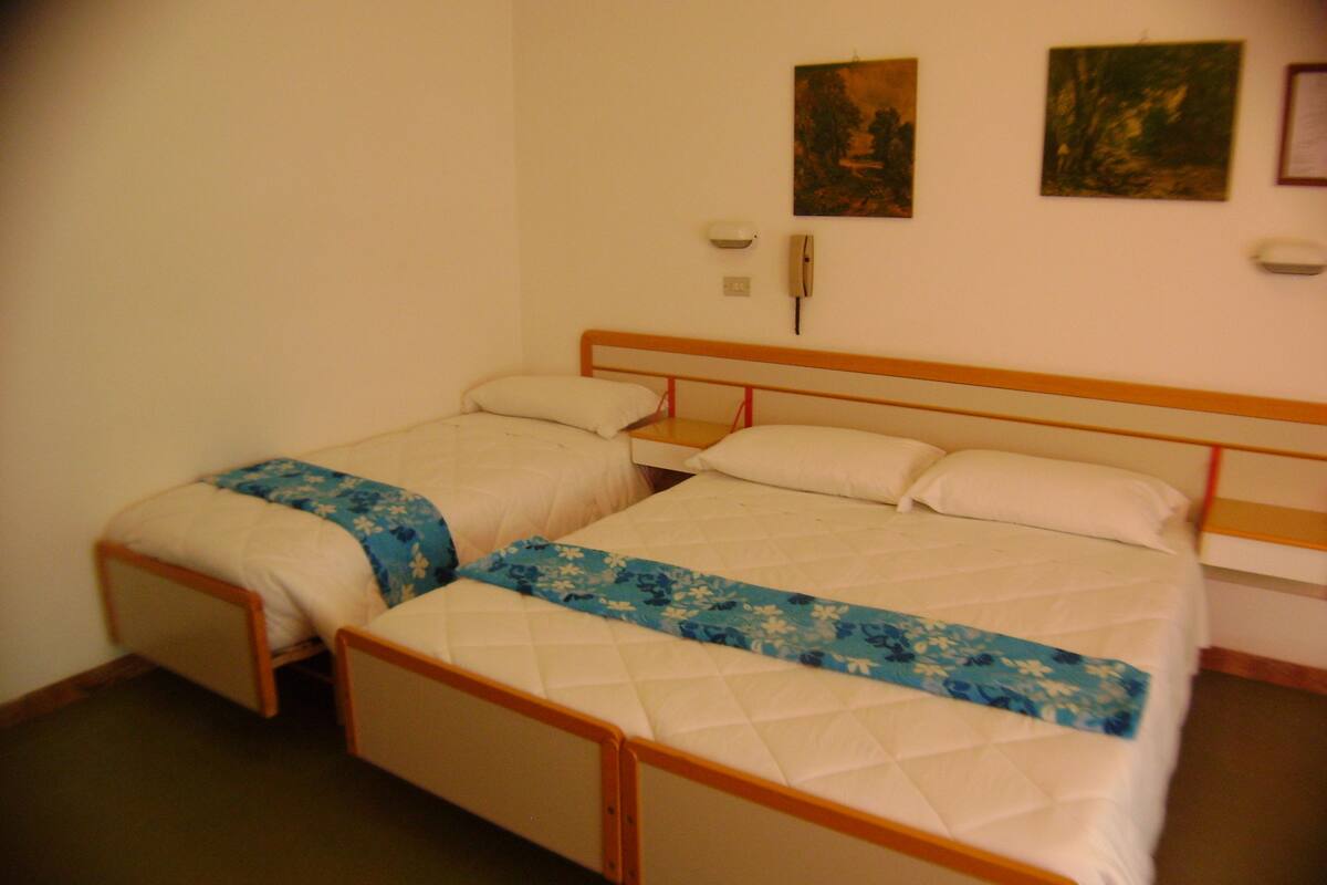 A double bed with a wooden headboard, two bedside tables, and a floral bedspread.