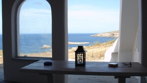 Uitzicht vanuit een kamer met een tafel en een raam, uitkijkend op de zee.