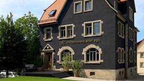 A two-story building with a dark facade, multiple windows, and a red-tiled roof. - Aparthotel Mittermeiers Alter Ego (Rothenburg ob der Tauber)