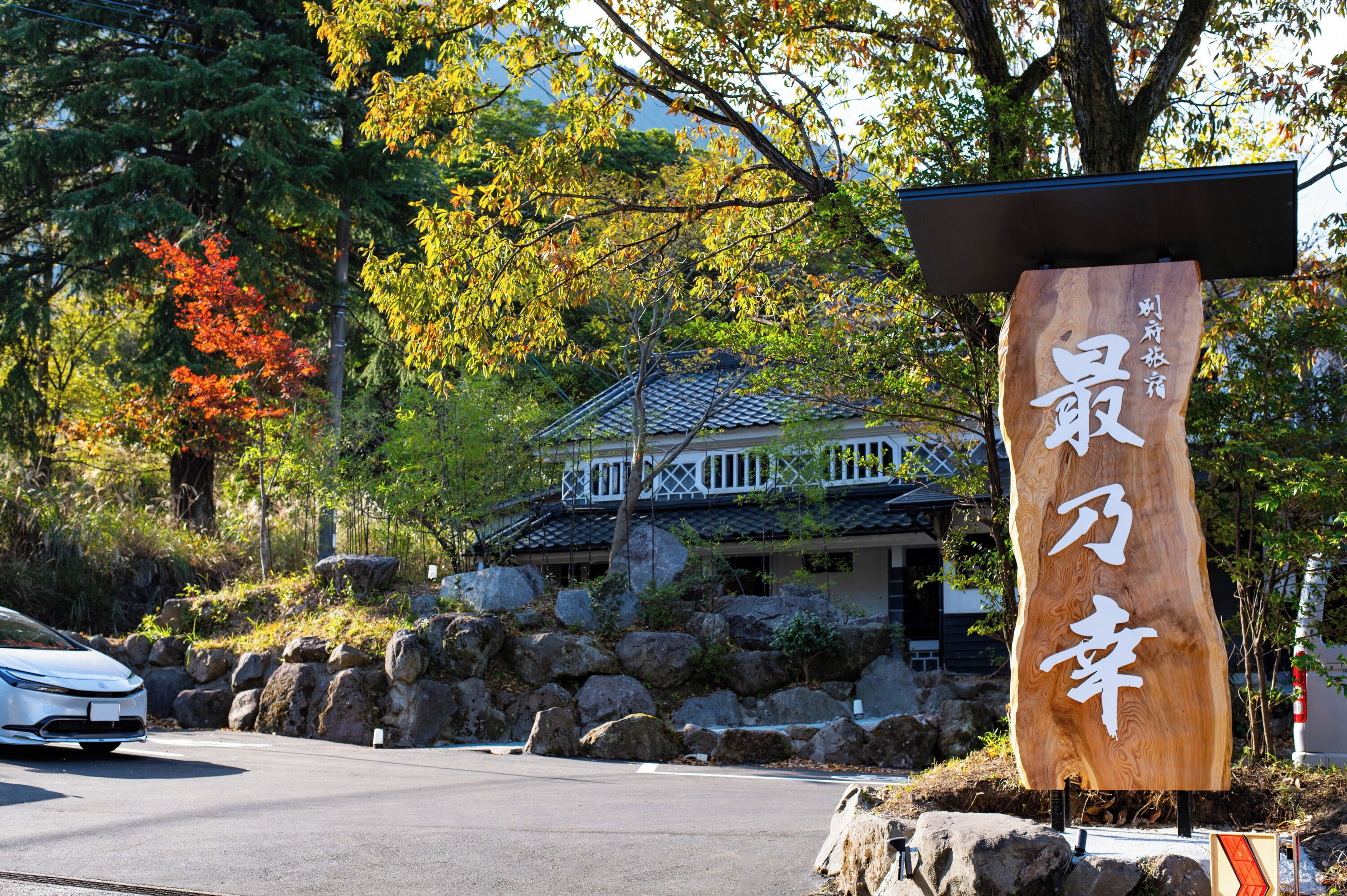 A traditional Japanese building with a wooden signboard, surrounded by rocks and trees.