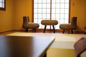 A tatami mat room with three woven chairs and a low table. - Beppu Tabiyado Sainokou (Beppu)