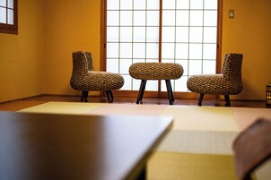 Una habitación con tatami, tres sillas tejidas y una mesa baja.