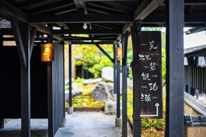 A covered walkway with directional signage and a view of a garden. - Beppu Tabiyado Sainokou (Beppu)