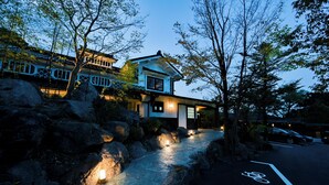 A traditional building with a stone pathway leading to the entrance, surrounded by large rocks and trees. - Beppu Tabiyado Sainokou (Beppu)