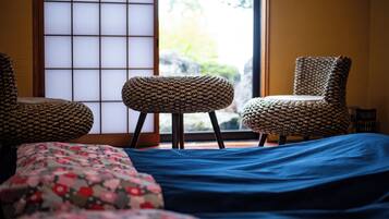 A traditional Japanese-style room with tatami flooring, a low table, and two chairs.