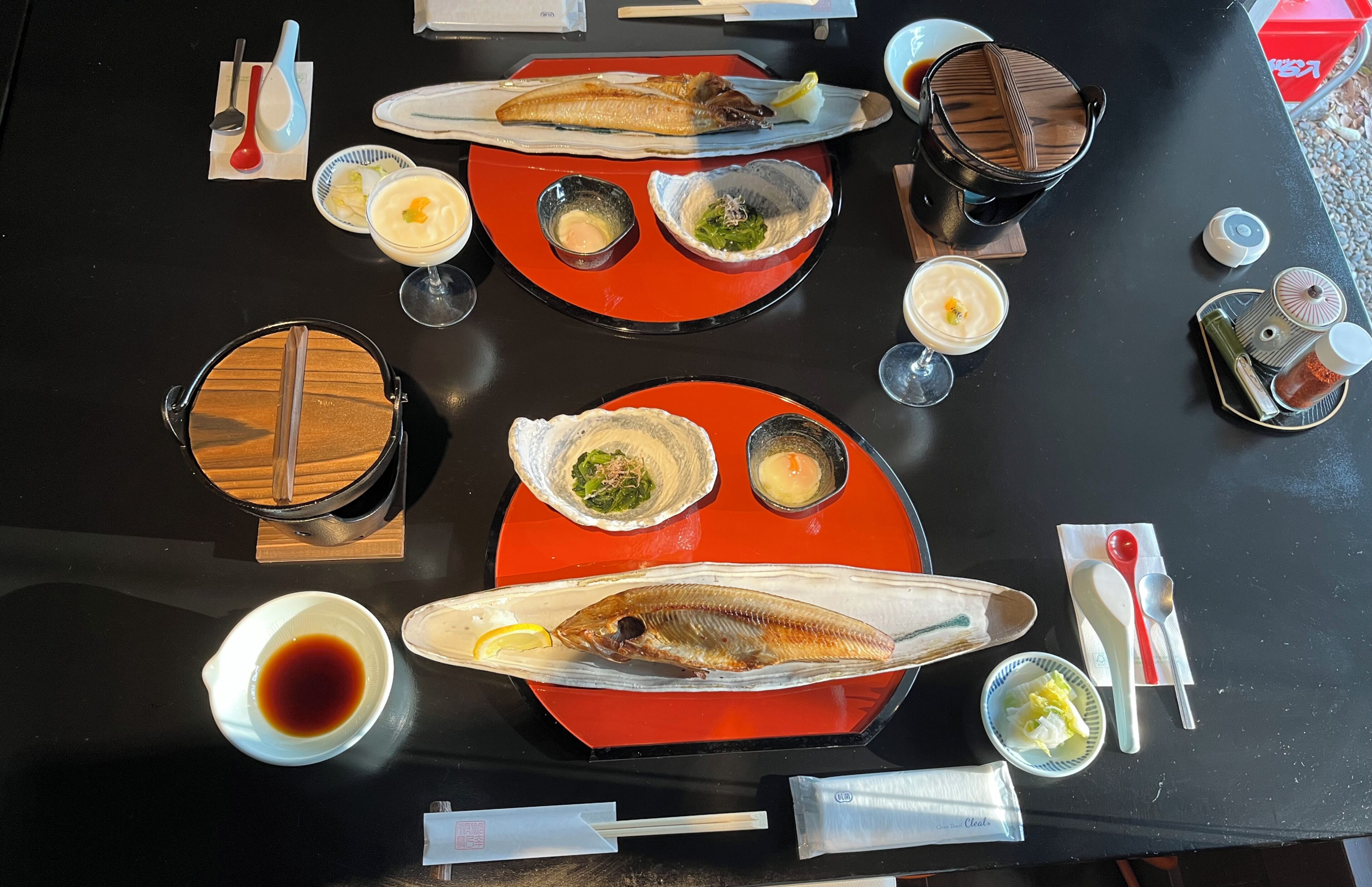 A dining table with various dishes, including fish, bowls of soup, and condiments.
